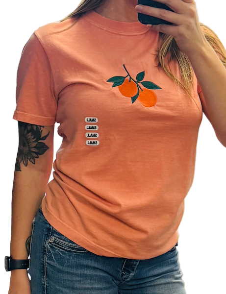 Person wearing an orange t-shirt with a graphic design, standing indoors.
